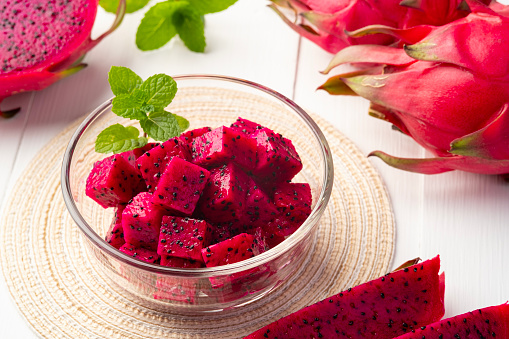 Close up sliced Red Dragon fruit in glass bowl on wooden plate background