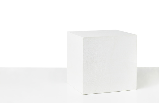 White painted wooden cube on table isolated on white background. Empty podium.