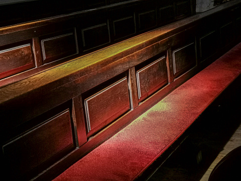 Parts of pews with red seat cashion in sunlight