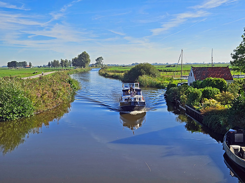 View on cruising motor boat in the countryside from Friesland in the Netherlands
