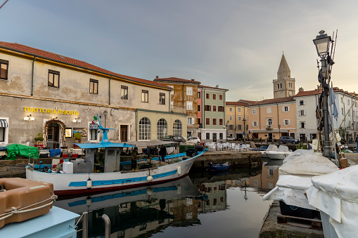 Muggia, Italy – November 18, 2023. Evening atmosphere in  the old harbour of Muggia, a coastal town in northern Italy near Trieste with moored small motor boats.