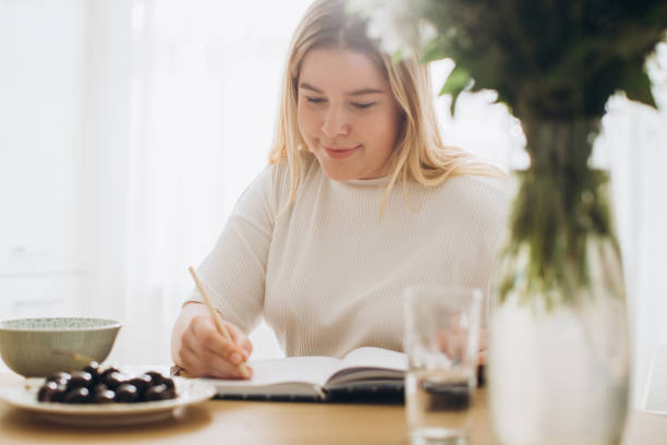 istock A beautiful young woman makes notes in her diary while having breakfast in the kitchen. 1807823454