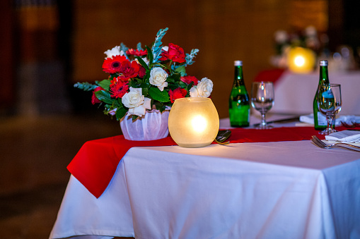 Christmas dinner table set up in restaurant with festive decorations, ornaments, red chair bows and tableware