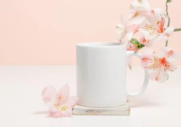 Photo of Mock-up mug on wooden cup coaster with pink lily flowers, copy space