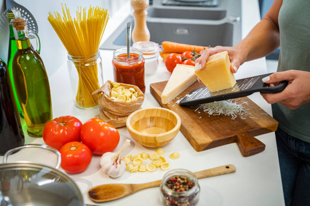 Woman grates Parmesan cheese  on kitchen counter