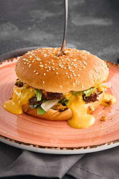 istock A succulent pulled beef burger dripping with rich cheese sauce, served on a plate for a mouthwatering meal 1807891586