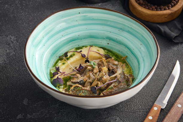 istock Classic beef stroganoff paired with smooth mashed potatoes, served in a bowl with a side of cutlery and spices on a black surface 1807891599