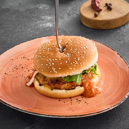 A delectable chicken burger topped with sweet and sour sauce, served on a plate for a satisfying meal.