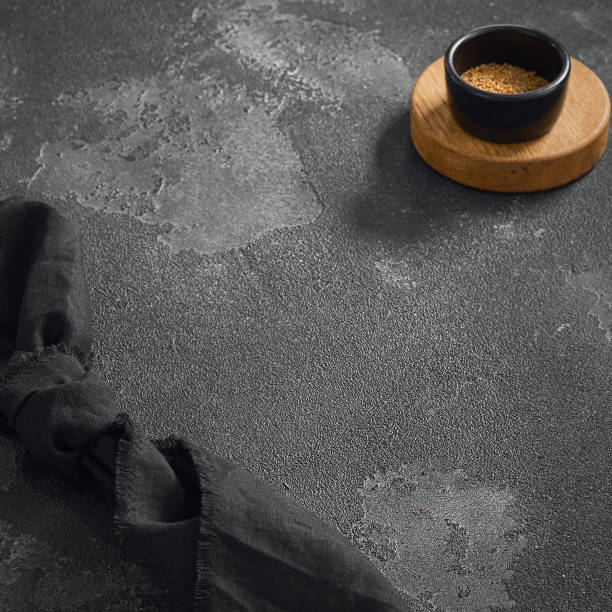 istock Minimalist composition featuring a black textured table with a wooden coaster and bowl of spices, perfect for culinary themes with ample copy space 1807892696