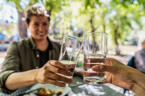 Close-up of persons toasting with glass of water at restaurant