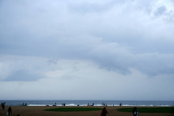 Rainy clouds over the sea. Group of people visiting Marina beach during the Monsoon season in Tamilnadu.