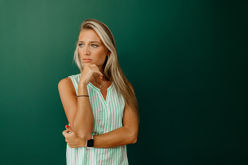 Attractive worried woman on green background