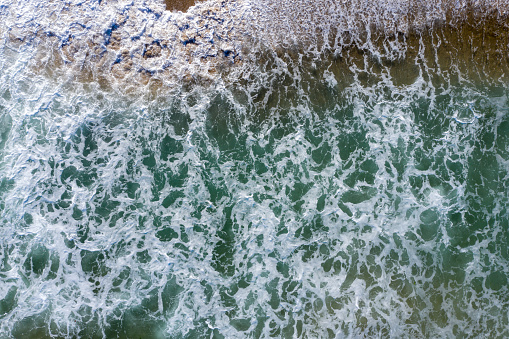 Aerial view of wild ocean waves crushing the beach by drone