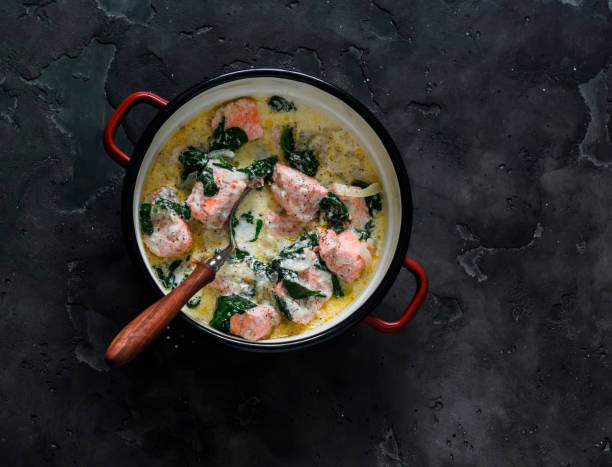 istock Salmon, cream, spinach sauce stew in a saucepan on a dark background, top view 1807918321