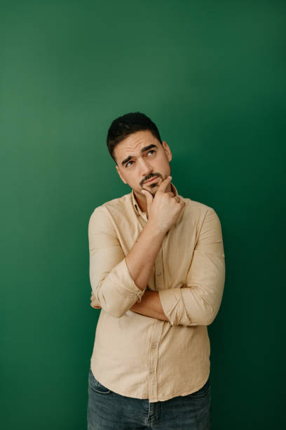 istock Young man holding chin with hand and looking up 1807919416