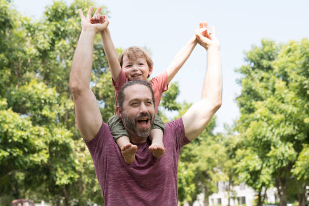 istock Happy father piggybacking cute little son on back outdoors. Cheerful dad playing, having fun and spending time together with little son in the park 1807926417
