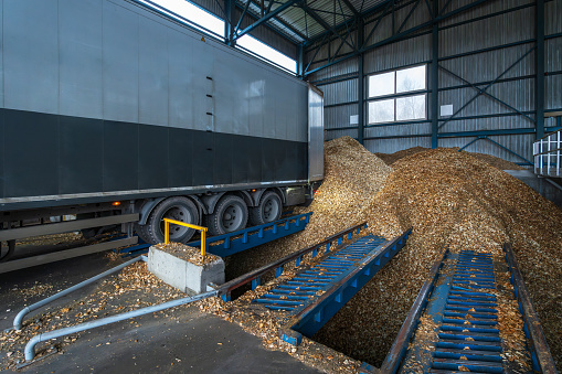 A truck with a full body of grain stands next to a truck unloading station at a grain terminal
