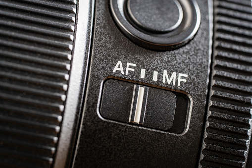 Close up of the auto or mannual focus button on the new camera lens. Af and mf switch on the camera lens, controls of a mirrorless camera, macro
