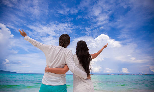 istock Back view of young couple spread their arms on beach 180796855