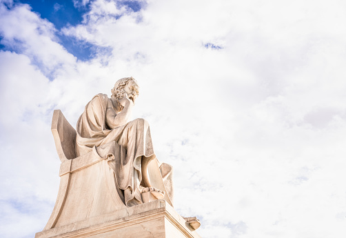 The marble statue of the ancient Greek philosopher Socrates, located at the Academy of Athens, against a dramatic bright sky.\n\nThe statue was completed in 1885 by Leonidas Drosis.
