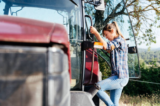 istock Young woman climbing on tractor at farm 1807998689