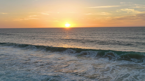 Slow motion of large waves of the Atlantic Ocean illuminated by sunset light. Cinematic drone of sunset over the sea. aerial view.