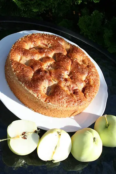 Cake, with Transparent Blanche apples, on white plate standing in garden on glass table
