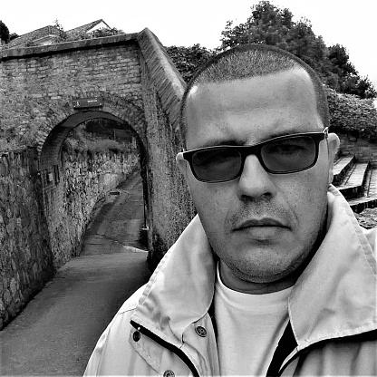 Black and white photo of a 39-year-old man, wearing dark glasses and a serious face.