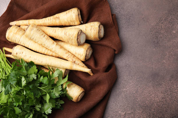 istock Whole raw parsley roots and bunch of fresh herb on brown table, flat lay. Space for text 1808040016