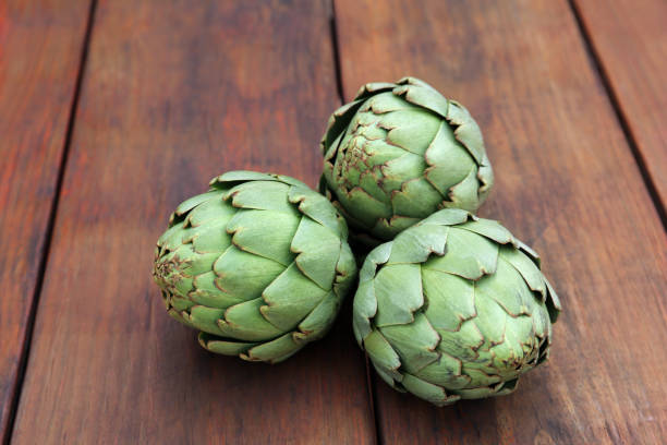istock Fresh raw artichokes on wooden table, closeup 1808042182