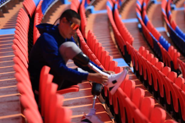 istock Asian man with a prosthetic running blade sitting on stadium bleachers 1808048008