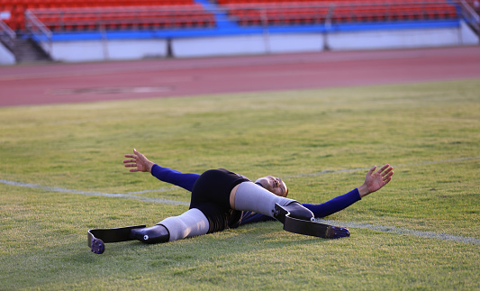 sportsman warming up before running practice on a grass field  stadium  stretching muscles on track,