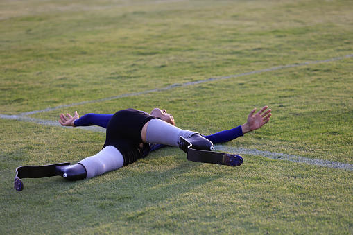 sportsman warming up before running practice on a grass field  stadium  stretching muscles on track,