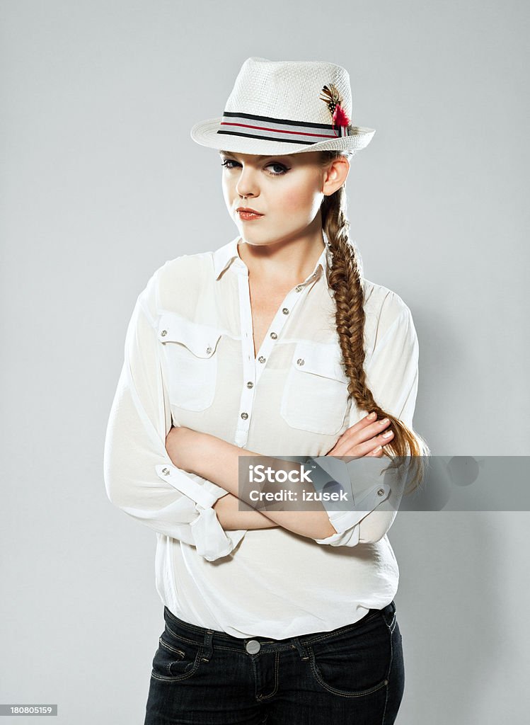 Disappointed young woman Portrait of disappointed young adult woman wearing hat standing with crossed arms. Studio shot on grey background. 20-24 Years Stock Photo