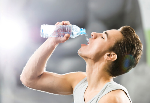Thirsty young man drinking water after exercising.