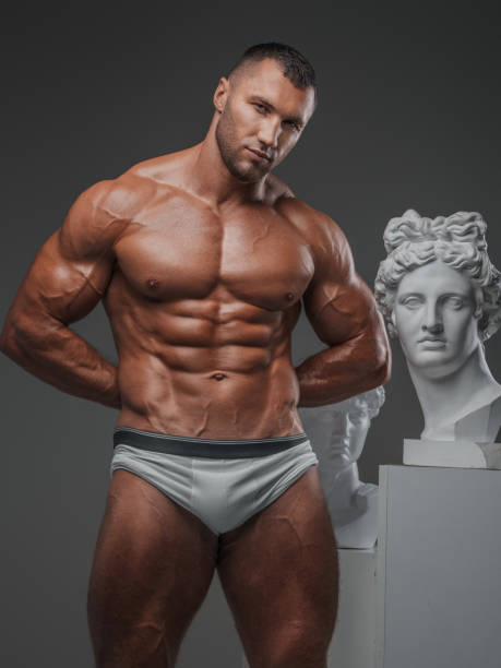 istock Rugged Beauty: Muscular Man and Ancient Greek Statues 1808053342