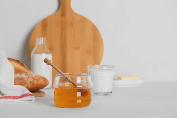 istock Jar with honey, milk, butter and bread served for breakfast on table. Space for text 1808053820
