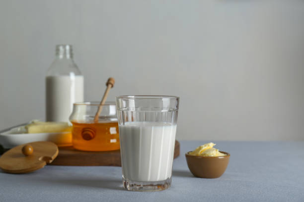 istock Glass with milk, honey and butter on grey table, space for text 1808056460
