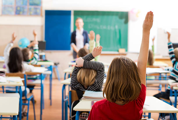 istock Children with their hands raised in a classroom 180805694