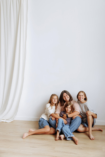 Happy mother and three daughters sitting on white background