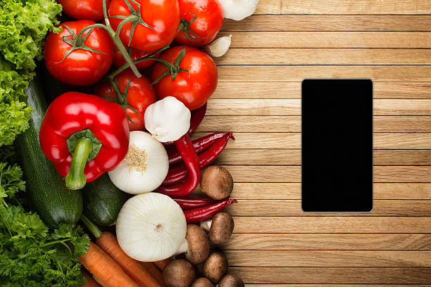 istock Smartphone on wooden surface with fresh vegetable mix 180805883