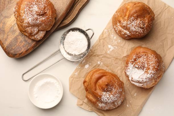 istock Delicious profiteroles with powdered sugar on white table, flat lay 1808063179