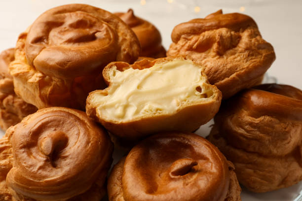 istock Delicious profiteroles with cream filling inside on white background, closeup 1808064241