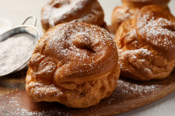 istock Delicious profiteroles with powdered sugar on wooden board, closeup 1808064452