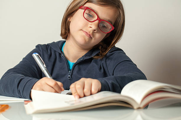 istock Little Girl Reading a Book and Taking Notes 180806900