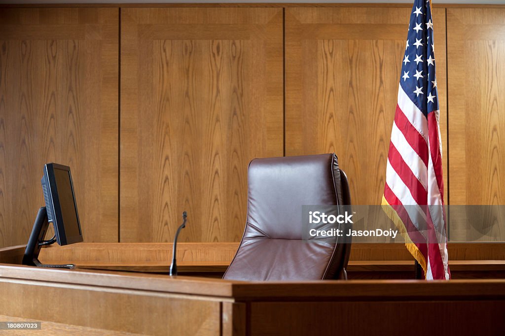 An empty courtroom bench with U S flag Courtroom bench in a wood panneled courtroom. Courtroom Stock Photo