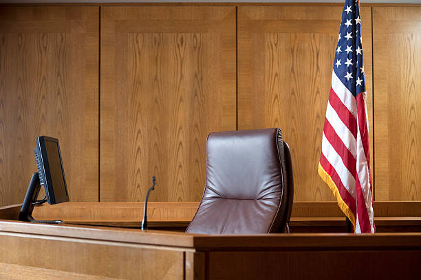 An empty courtroom bench with U S flag Courtroom bench in a wood panneled courtroom. legal trial photos stock pictures, royalty-free photos & images