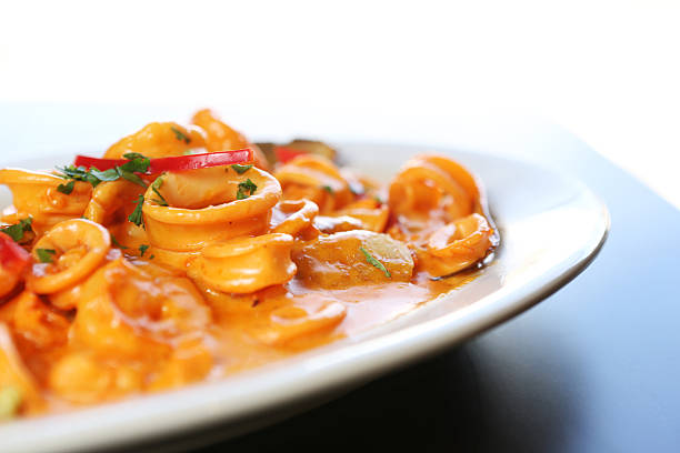 Delicious seafood pasta, clams, octopus and tomatoes served in a white plate on wooden table