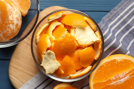 Orange peels preparing for drying and fresh fruits on blue wooden table, flat lay