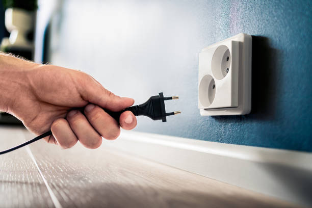 istock Socket, plug and electric power outlet. Man unplugging or holding cable wire cord in hand. Save energy. Electricity from home wall. Electrical current conservation. 1808086573